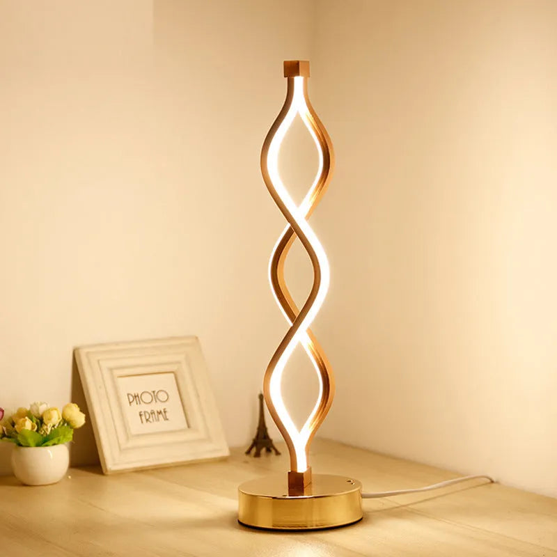 Gold LED desk lamp with acrylic shade and aluminium body on a desk