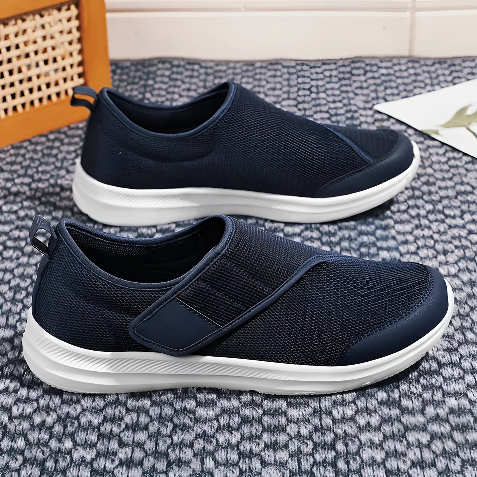A pair of grey Velcro walking shoes with a mesh upper and round toe, shown on a white background.