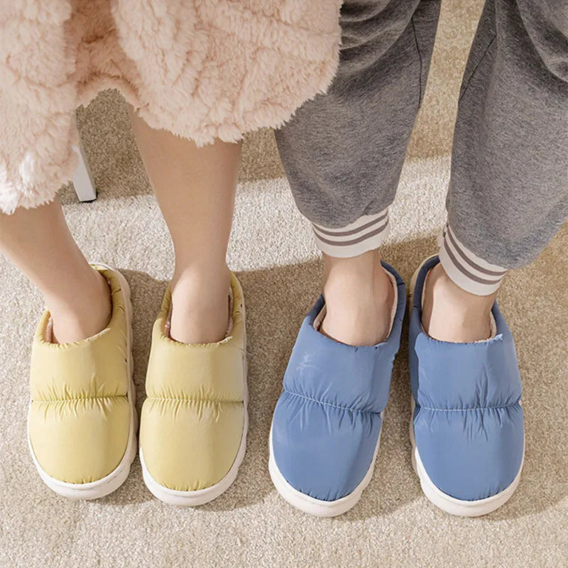 A pair of blue down cotton slippers with a thick sole, artificial leather upper, and plush lining for indoor winter wear.