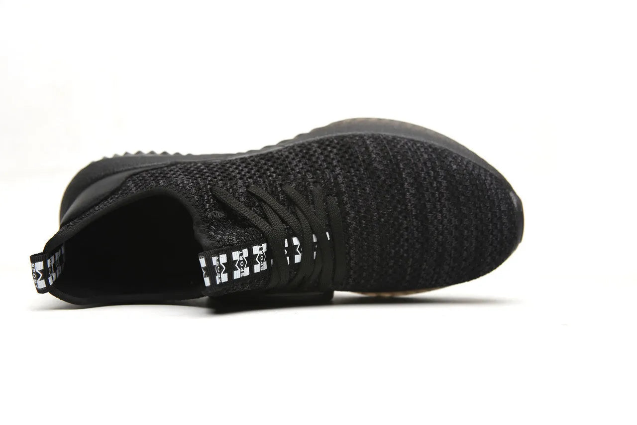 Black steel toe cap safety shoes with low-cut design on a work site background.