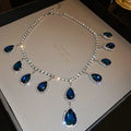 Silver needle water drop earrings and necklace set with blue zircon pendants and love heart bell pattern on white background