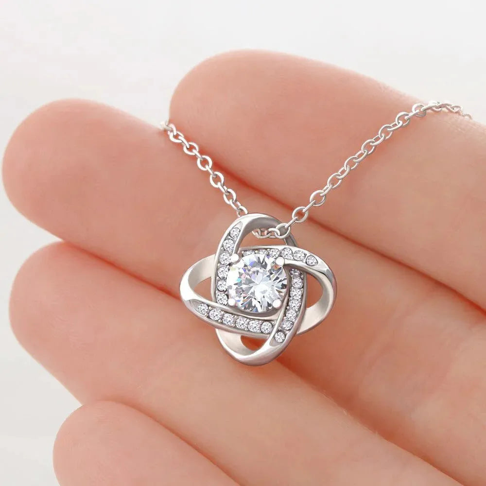 Silver metal four-leaf clover hollow jeweled pendant clavicle chain on display with geometric shape and card beside flip gift box