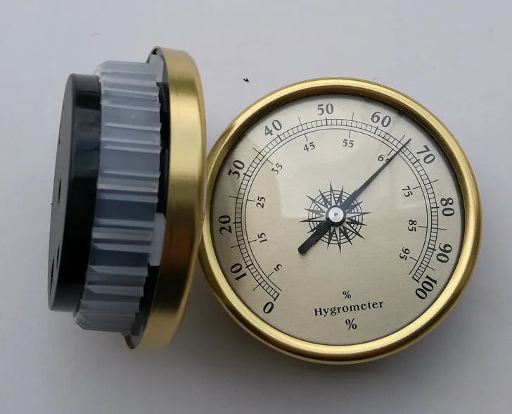 Analogue thermometer and hygrometer with aluminium ring and dial on a white wall.
