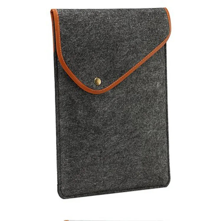 Flat felt bag computer bag in dark grey with magnetic buckle closure on a flat surface