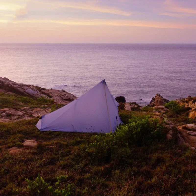 Silicon coated outdoor camping pyramid tent in green pitched on grass showing fly and aluminium pole