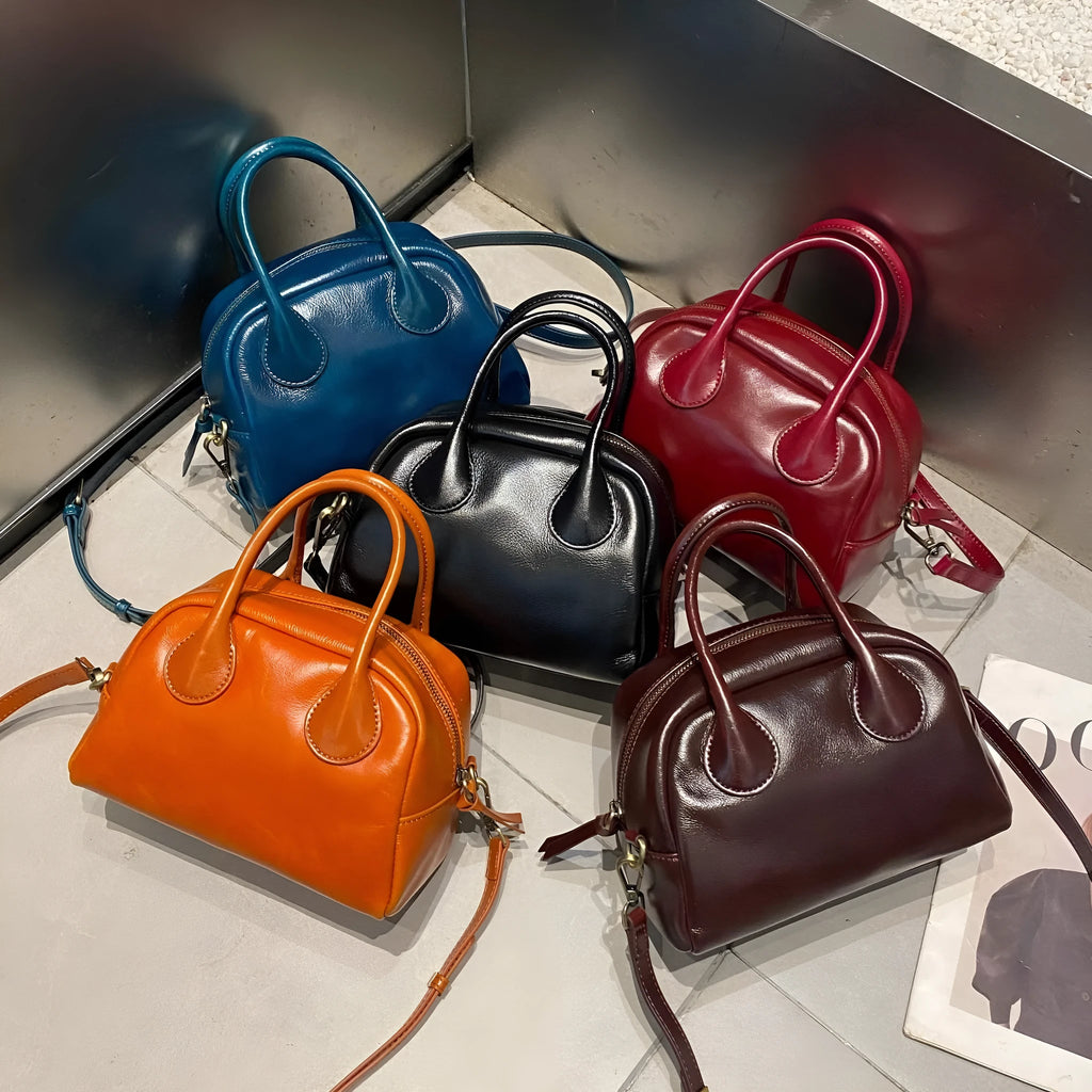 Genuine leather mini bowling bag in pillow shape with top grain finish and inner pockets.