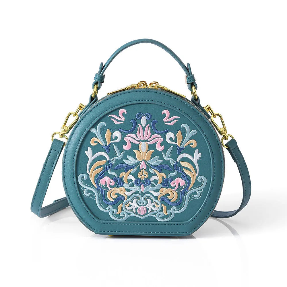 Small crossbody round bag in khaki with national-style embroidery and sewing line details, shown on a plain background