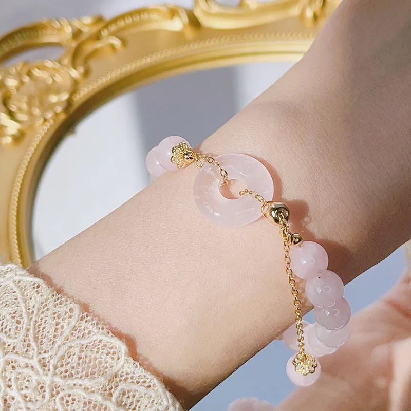 Pink crystal peace buckle bracelet on a metallic chain for women.