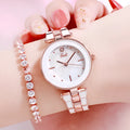 White dial ladies quartz watch with rose gold accents, steel strap, 30mm round alloy case on flat surface