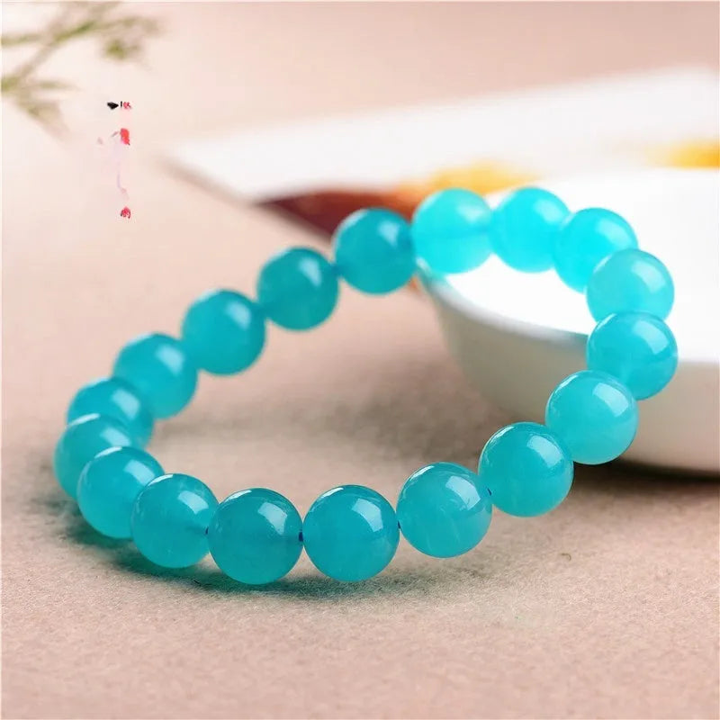 Natural blue-green Amazonite scattered loose beads in various sizes next to a finished crystal bracelet.