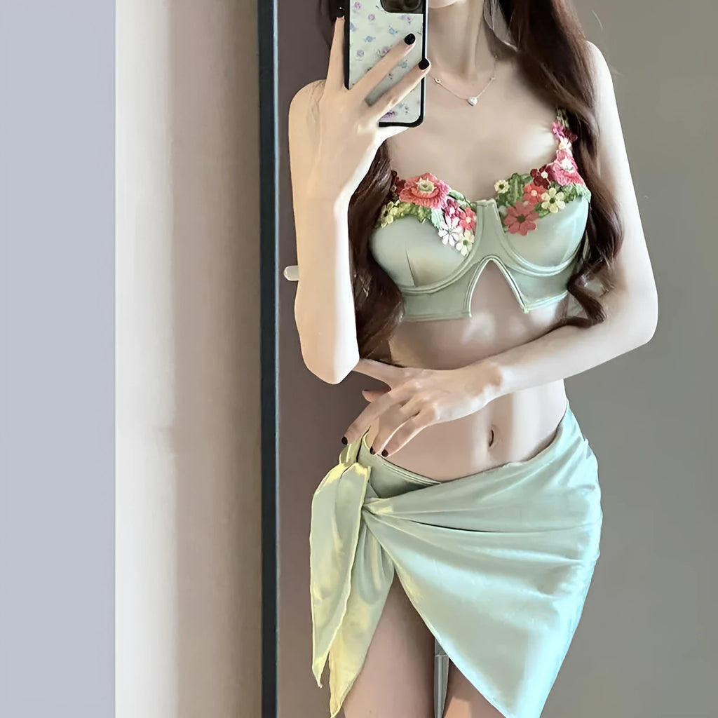 Green women's three-piece bikini set showing triangle top, briefs, and removable skirt laid flat.