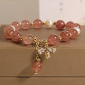 Close-up of a women's bracelet with pink strawberry quartz beads, white freshwater pearls, and sparkling zircon charms on an alloy chain.