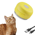 Green and yellow rechargeable silicone steam brush for pet grooming on a table.