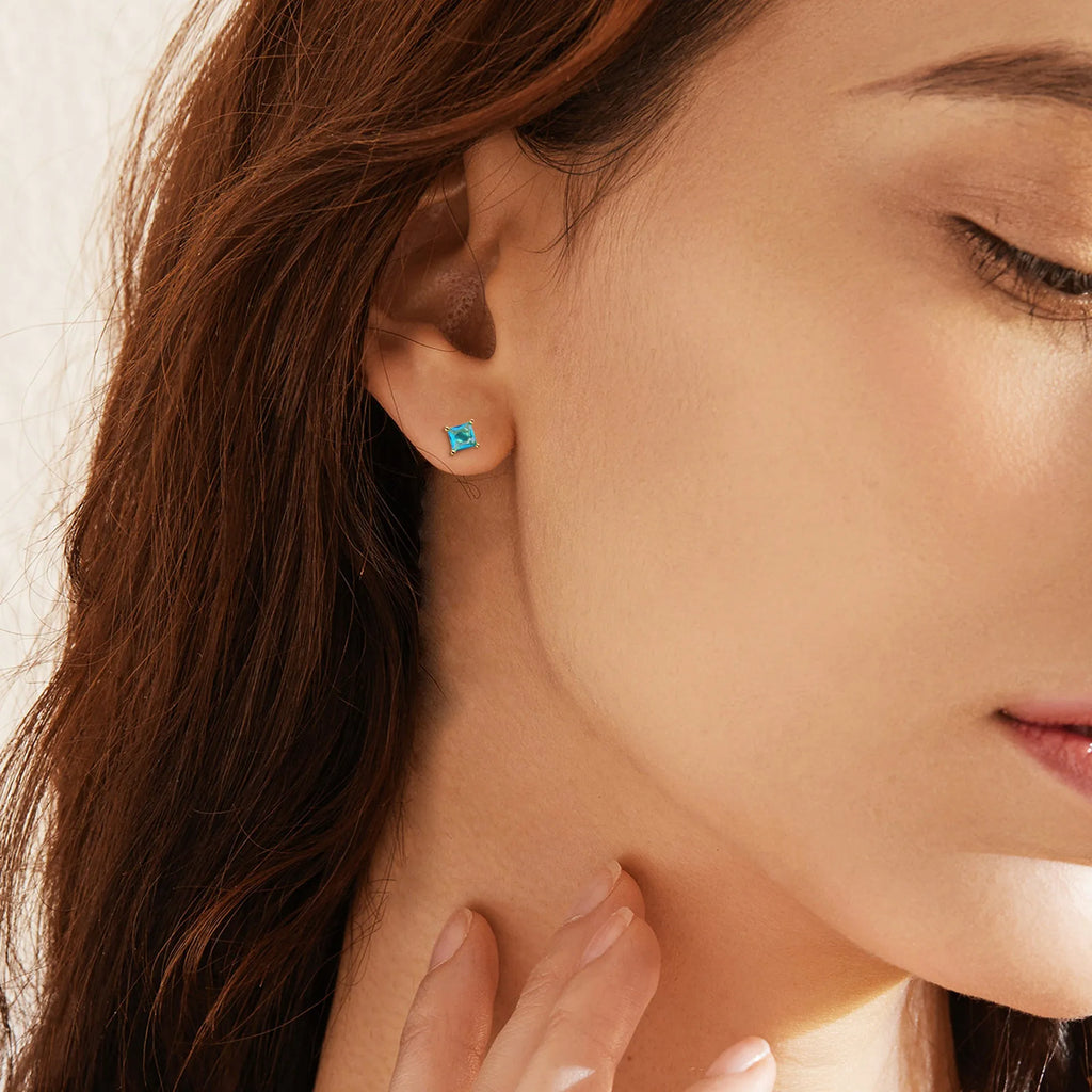 A pair of gold-plated drop earrings with candy-coloured pear-shaped zircon stones on a simple setting.