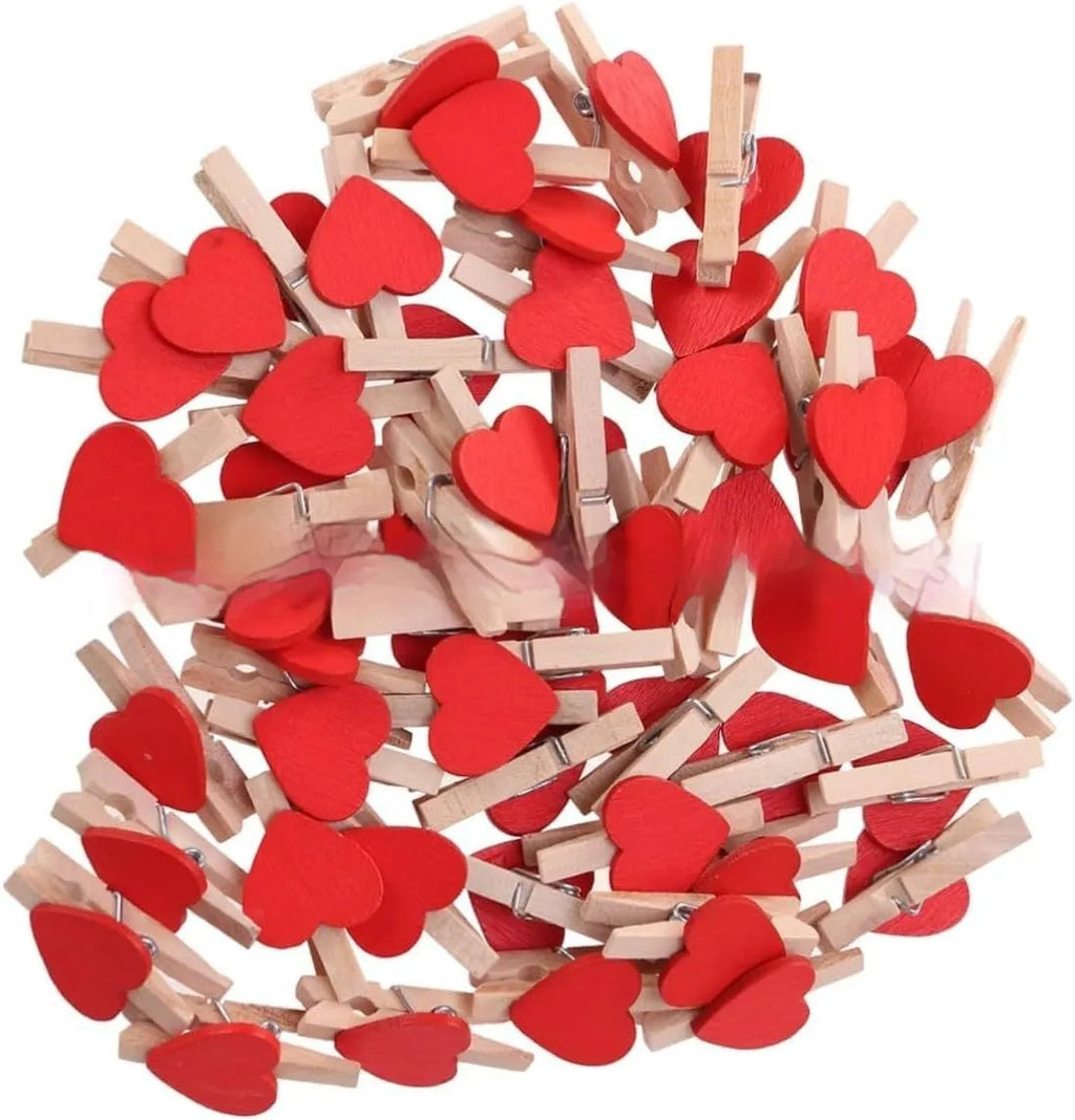 Set of five small red, pink, and white solid wood heart-shaped clips on a surface.
