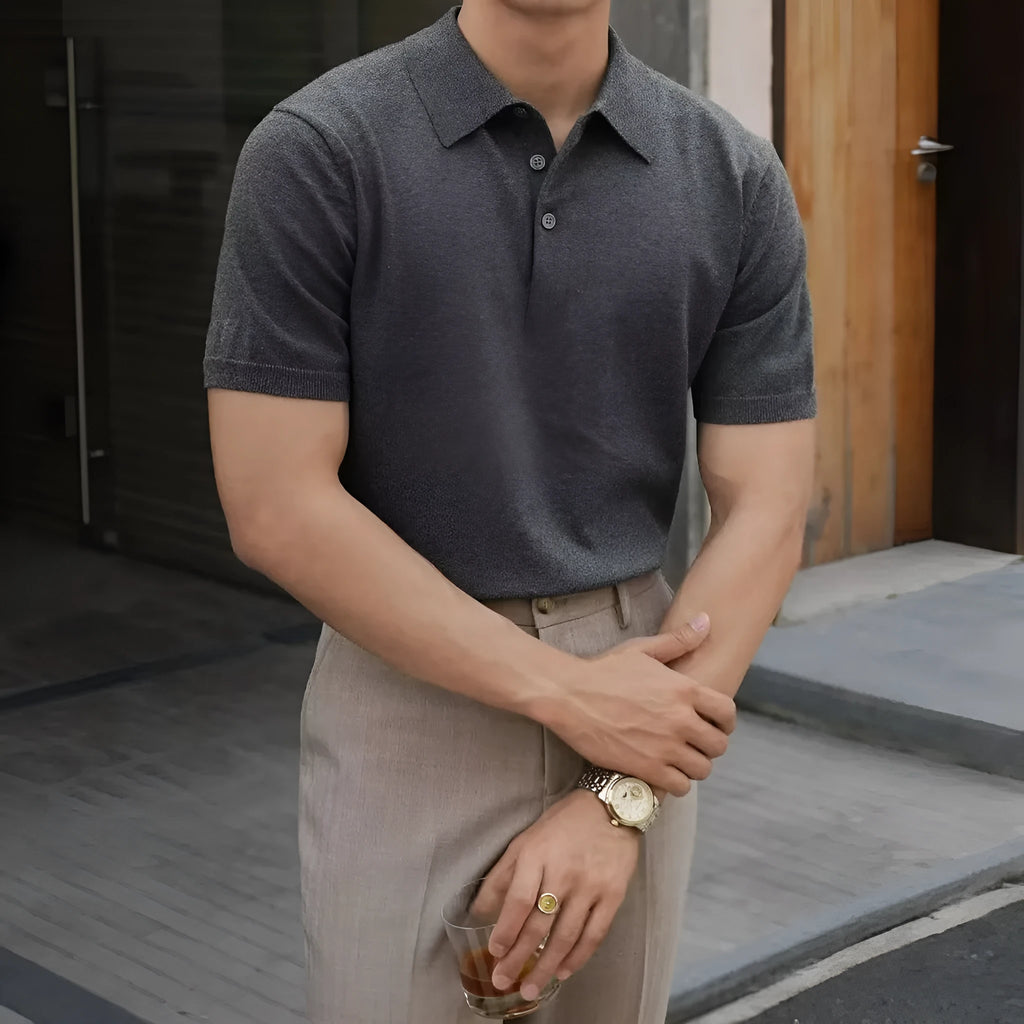 Men's black polo shirt with knitted collar and short sleeves laid flat.