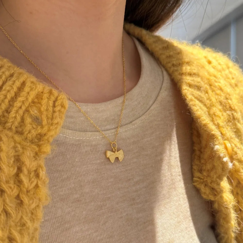 925 silver matte bow necklace with electroplated gold finish on display