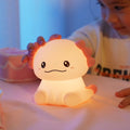 Hexagonal dinosaur-shaped silicone night lamp with warm white glow on a bedside table