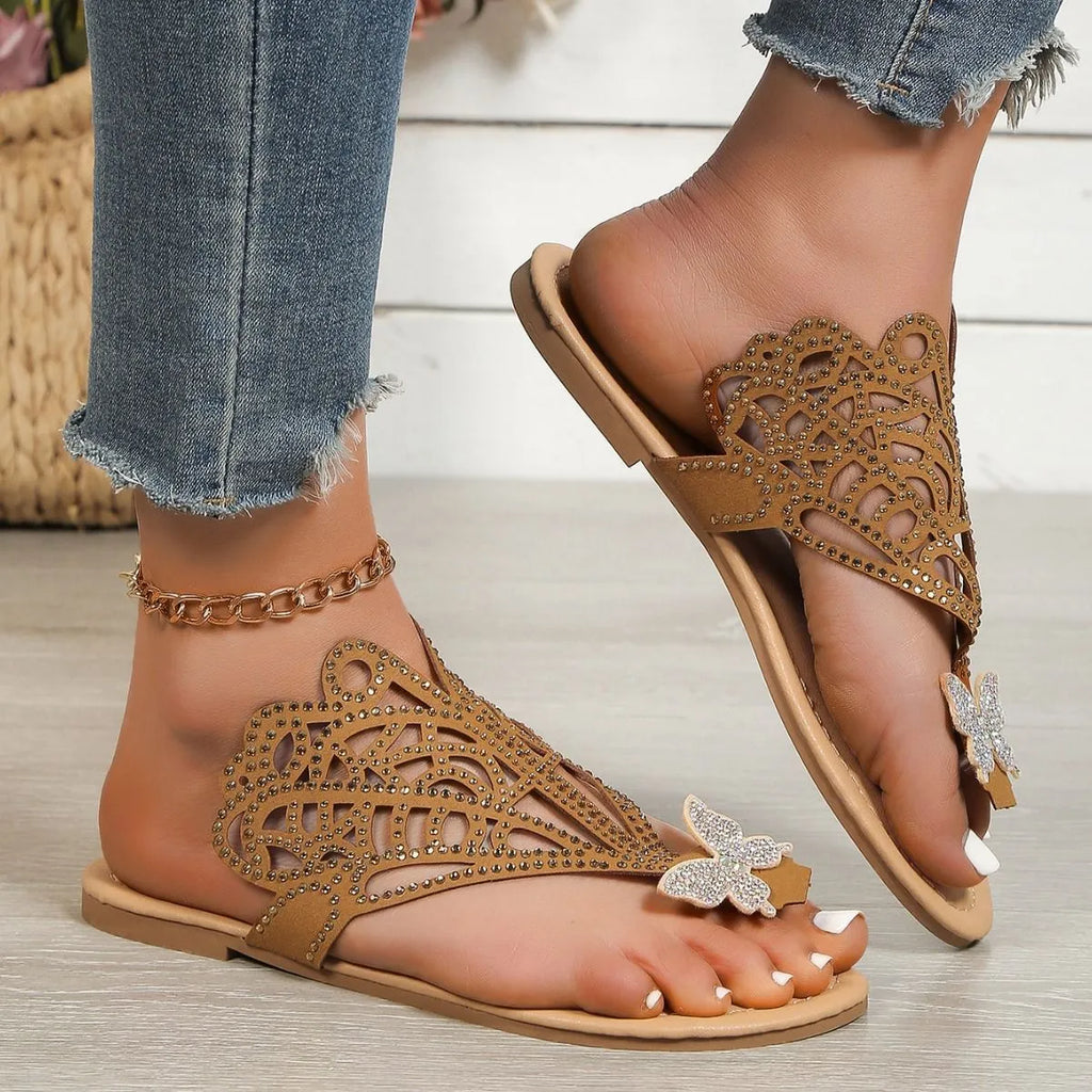 Women's black slip-on sandals with rhinestone decoration and a flip-toe design on a light background.
