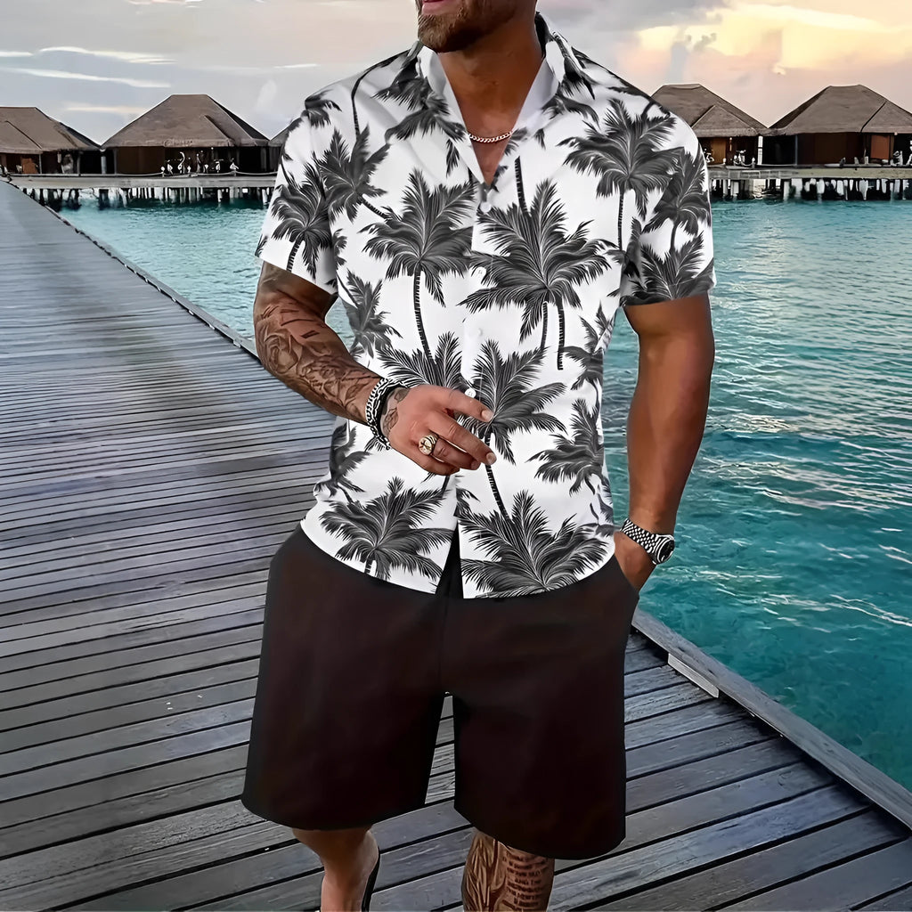 Man wearing a blue Hawaiian print short sleeve shirt and matching shorts from a casual suit set.