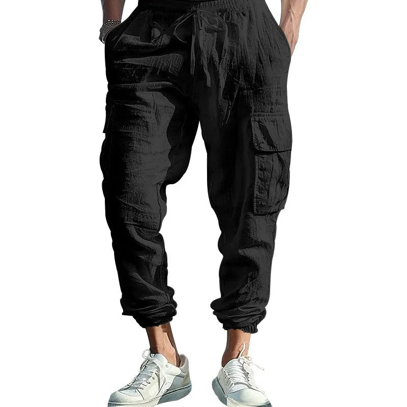 Man wearing loose khaki linen trousers with ankle-tied cuffs, drawstring waist, and multiple pockets.