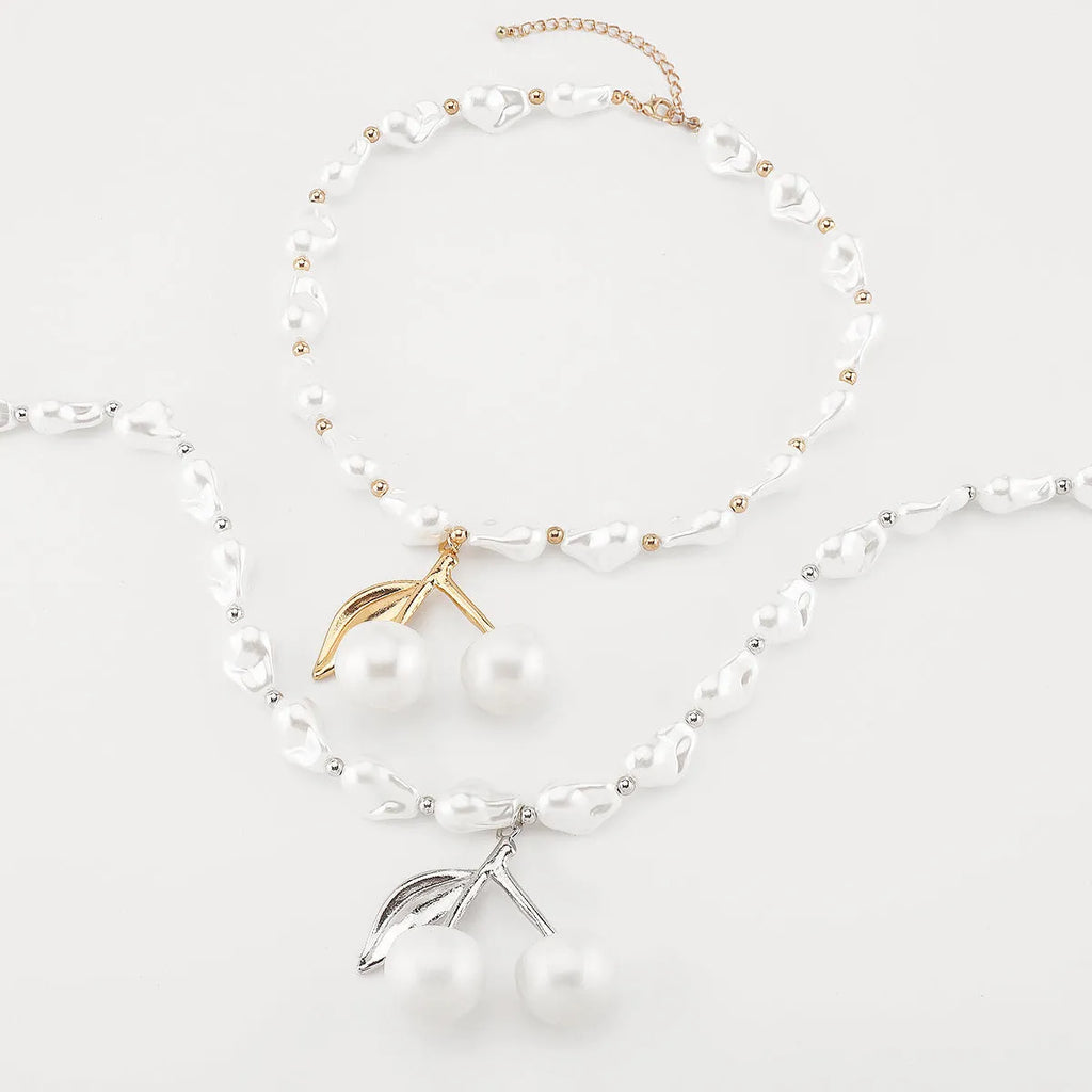 Gold-coloured women's necklace with a cherry fruit pendant on a pearl-style chain.