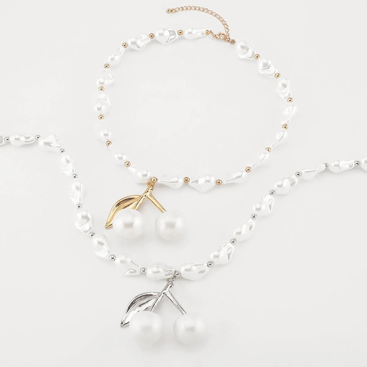 Gold-coloured women's necklace with a cherry fruit pendant on a pearl-style chain.