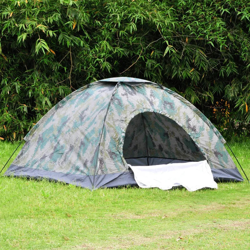 Green camouflage two-person camping tent with fibre glass poles and steel pegs pitched outdoors.