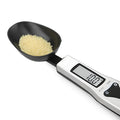 Smart digital kitchen measuring spoon with backlit LCD display showing weight and volume measurements.