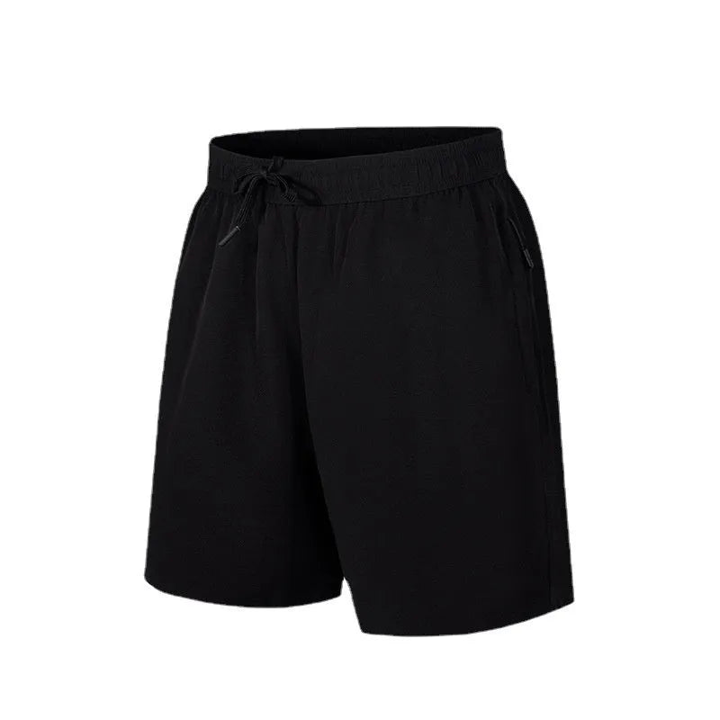 Man wearing loose-fitting quick-dry polyester sports shorts on a beach.