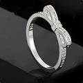 Silver couple ring with a bow shape set with rhinestones and zircon crystals.