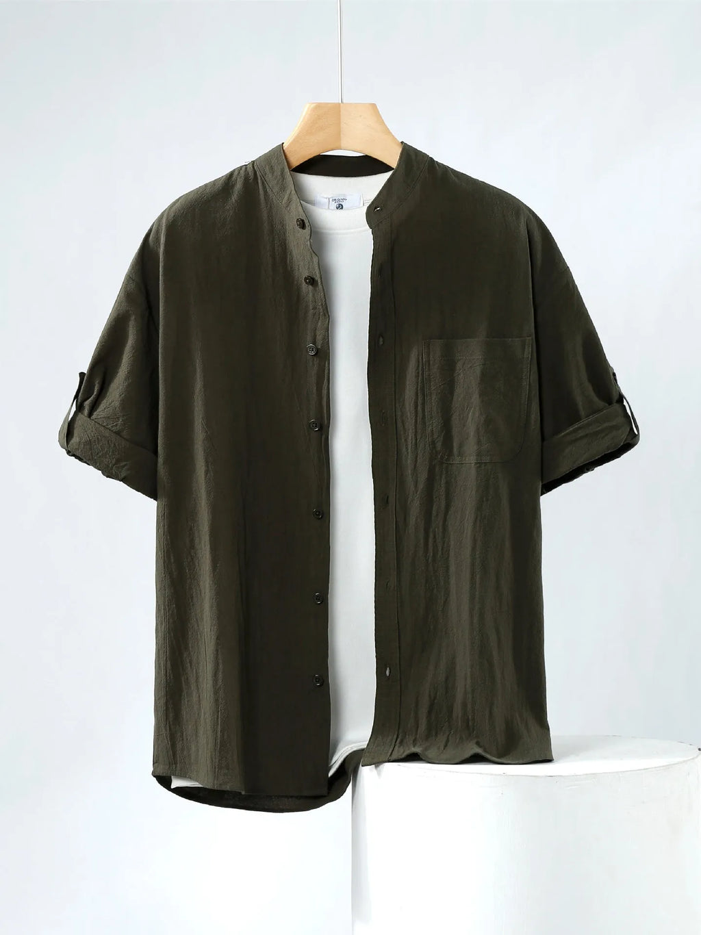 A man's loose-fitting, short-sleeved linen shirt in a solid colour with a stand collar.