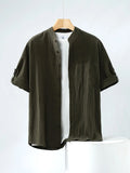 A man's loose-fitting, short-sleeved linen shirt in a solid colour with a stand collar.