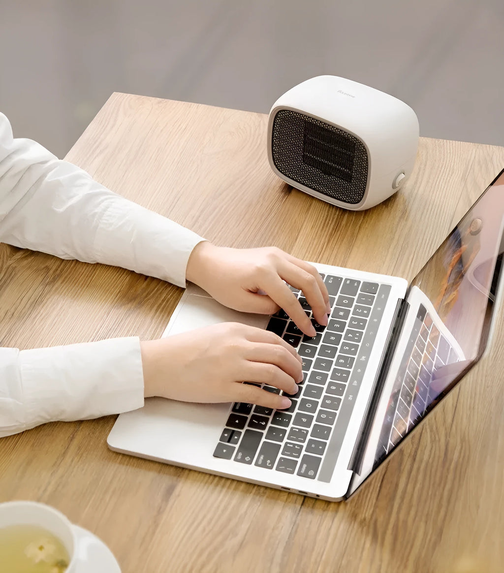 Compact green portable ceramic fan heater on a wooden desk