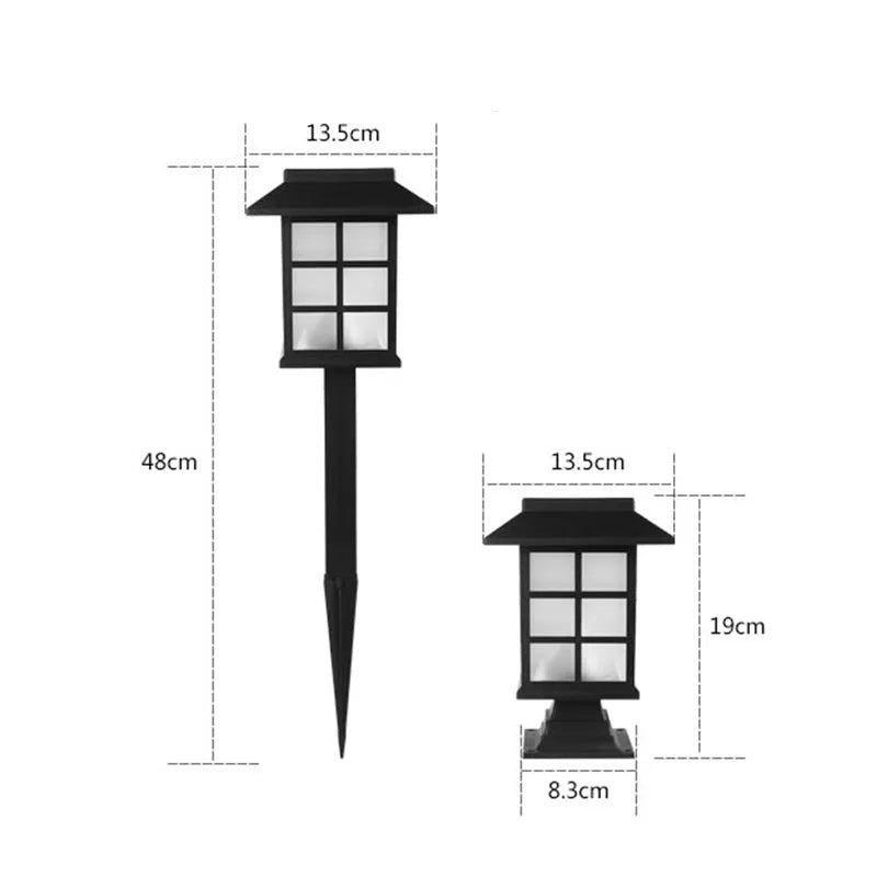 Black solar-powered outdoor LED lawn light with window-style openings, shown in a garden setting.