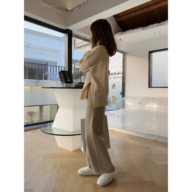 Woman wearing high-waist cream knitted wide-leg trousers with a floor-length, straight-leg silhouette.