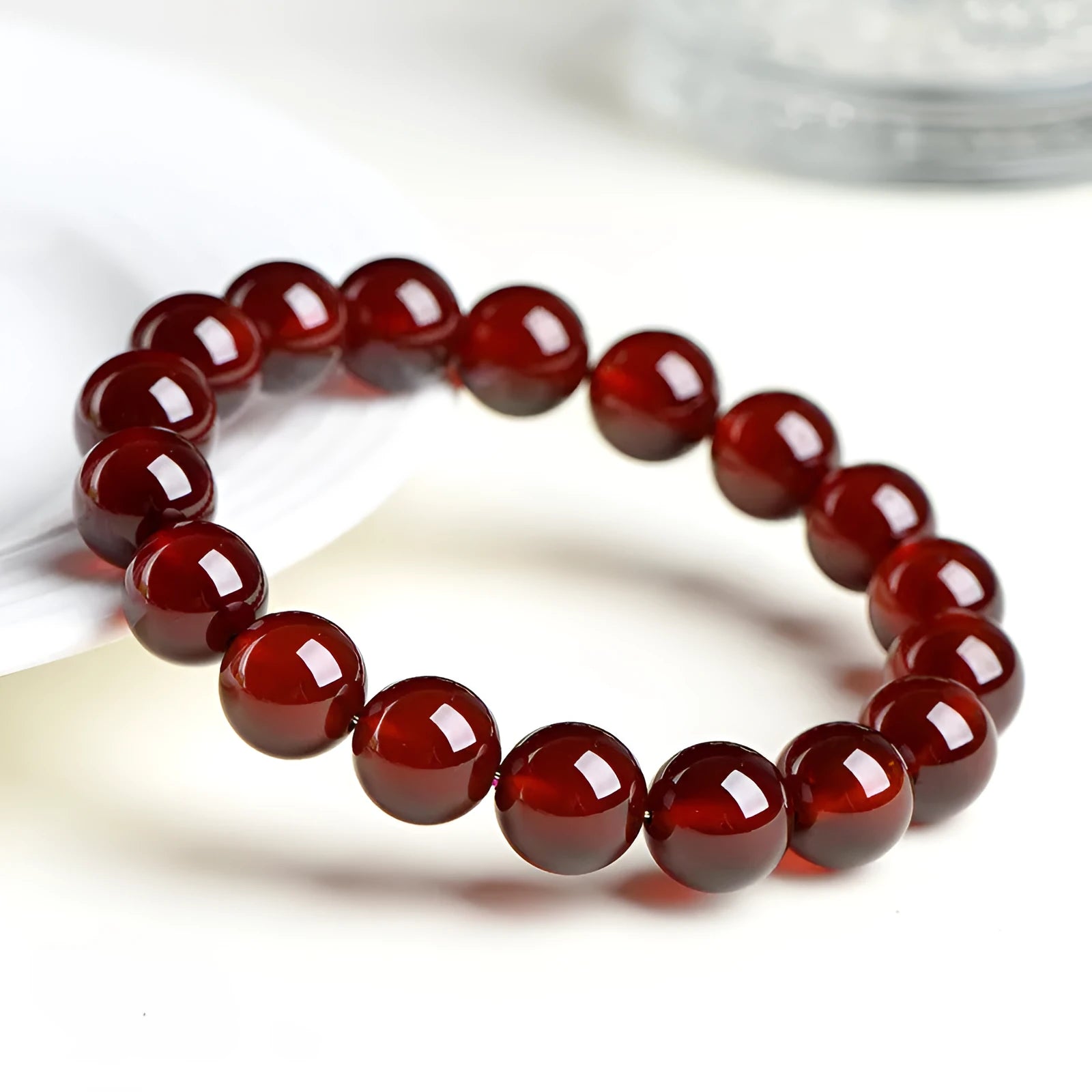 Natural orange red garnet ball crystal bracelet with a silver ruyi charm on a white background.
