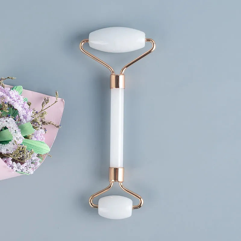 White jade double-headed facial roller and matching gua sha board set on a plain background.