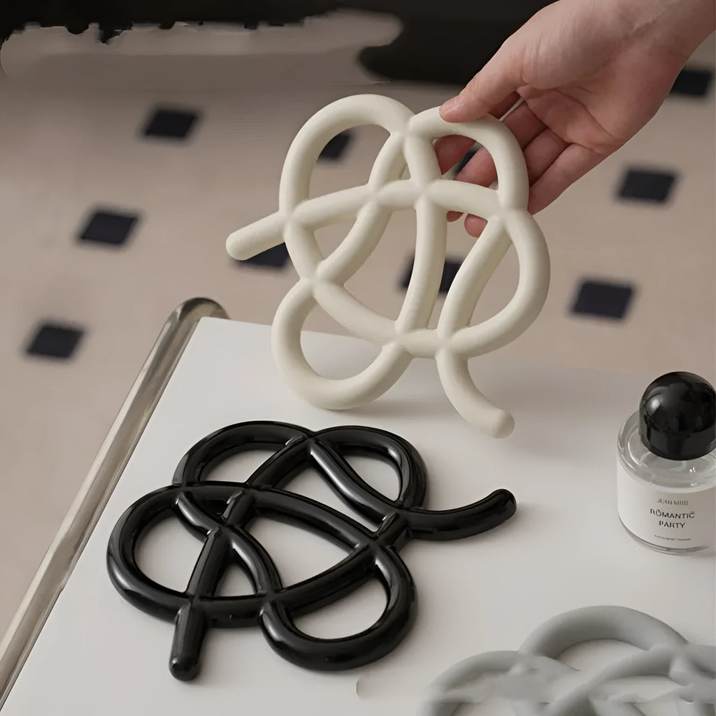 Ceramic heat proof mat in an irregular shape on a kitchen table, shown in a solid colour.