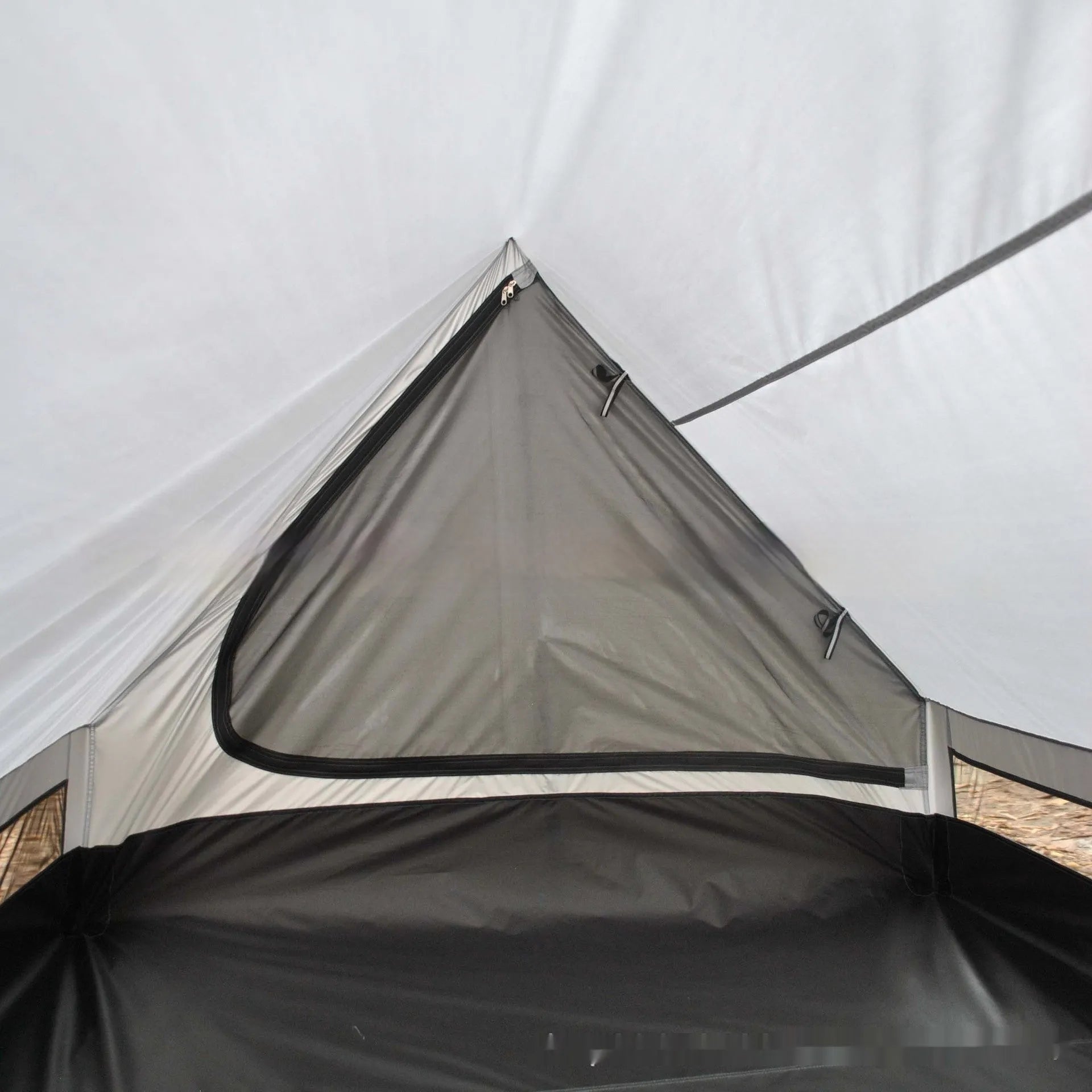 Lightweight brown A-line hiking tent set up with hiking cane supports in outdoor setting