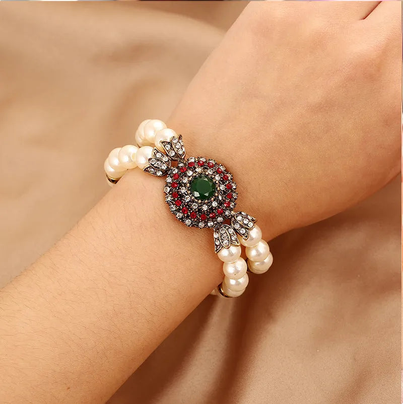 Luxury pearl bracelet in green and red alloy metal on display