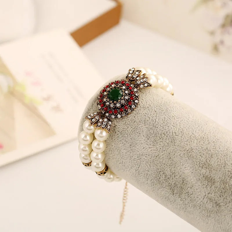Luxury pearl bracelet in green and red alloy metal on display