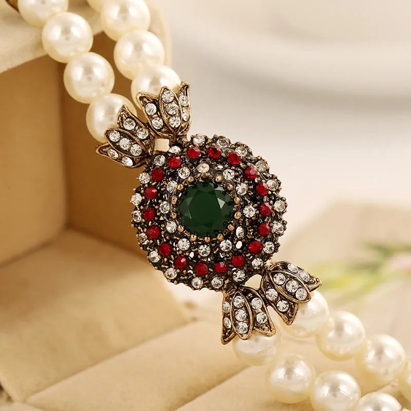 Luxury pearl bracelet in green and red alloy metal on display
