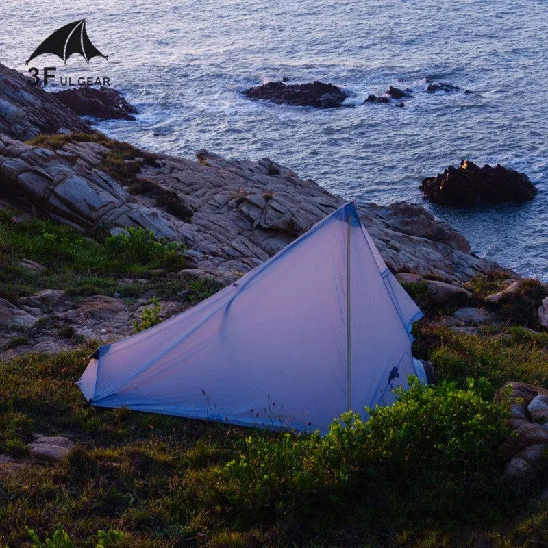 Silicon coated outdoor camping pyramid tent in green pitched on grass showing fly and aluminium pole