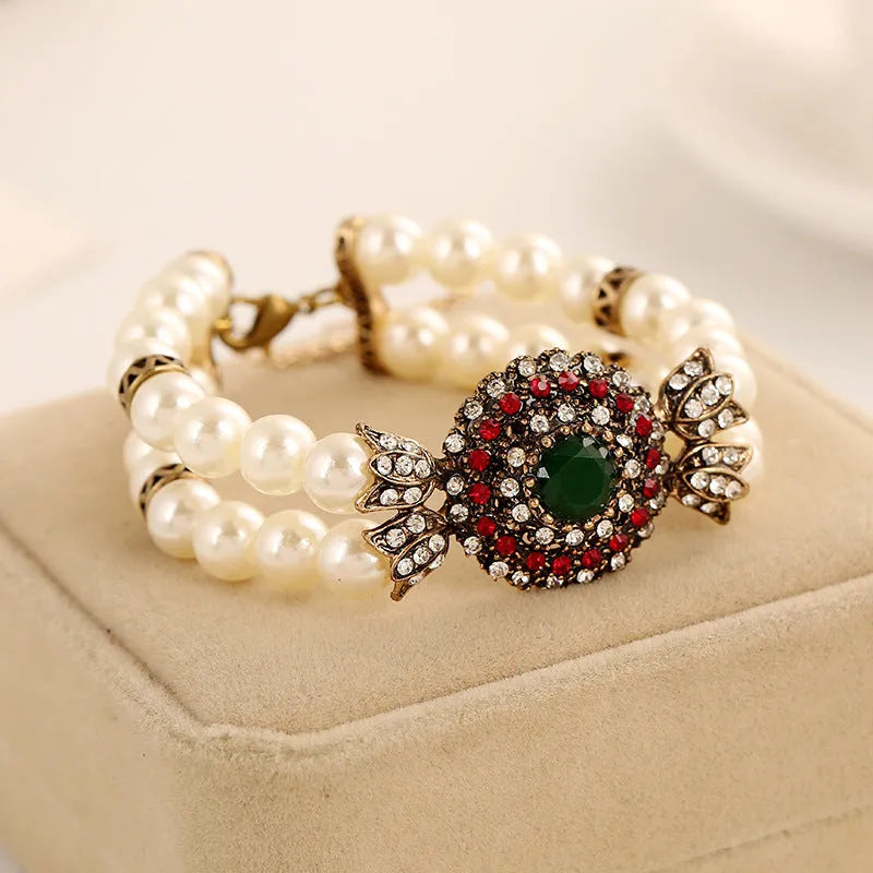 Luxury pearl bracelet in green and red alloy metal on display