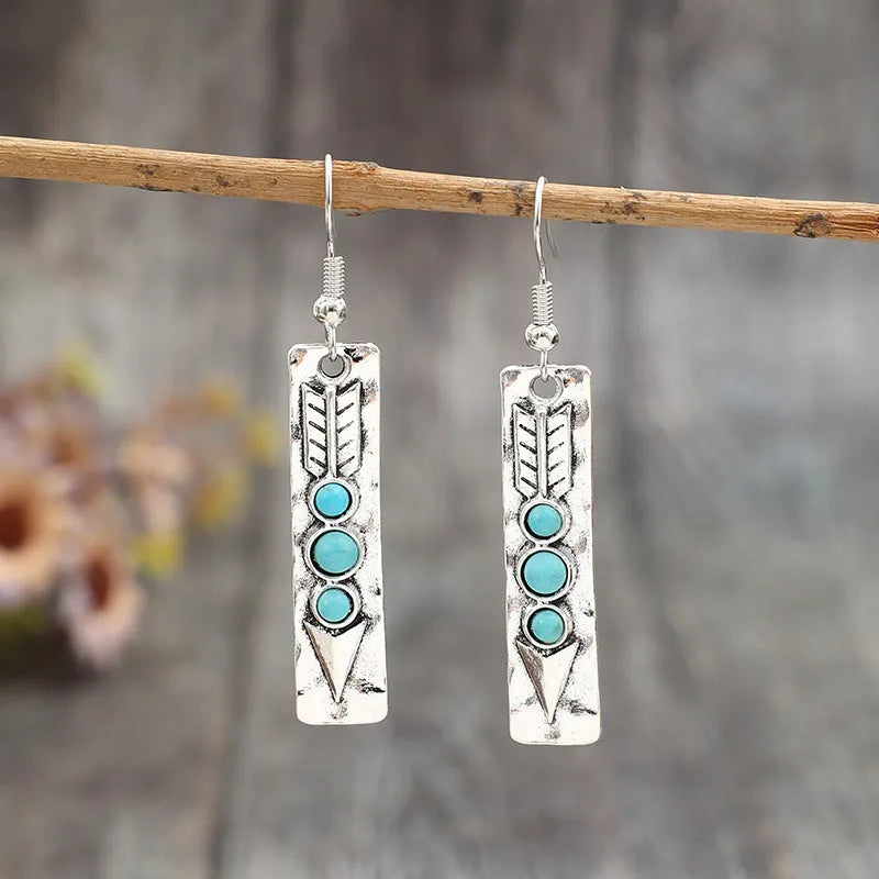 Long silver geometric drop earrings with inlaid turquoise details on a retro-style zinc alloy setting.