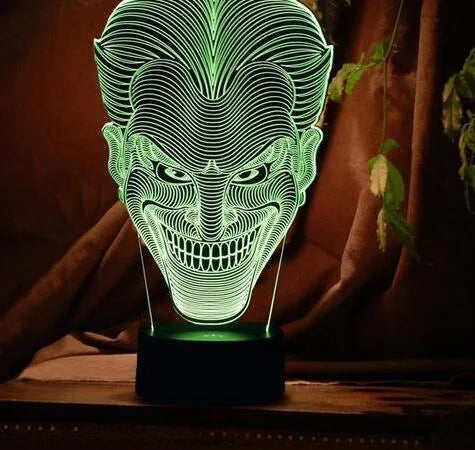A 3D acrylic LED table lamp displaying colourful light patterns, with a remote control and USB cable.