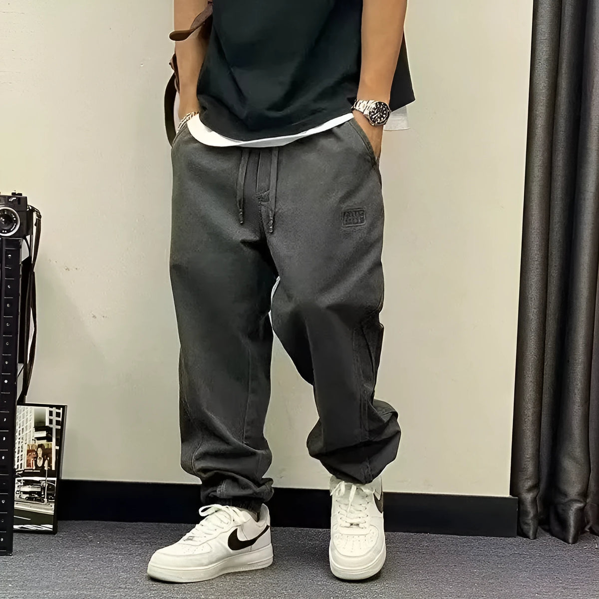 Men's black cotton harem pants with elastic waist and drawstring, cropped ankle bandage leg, side view