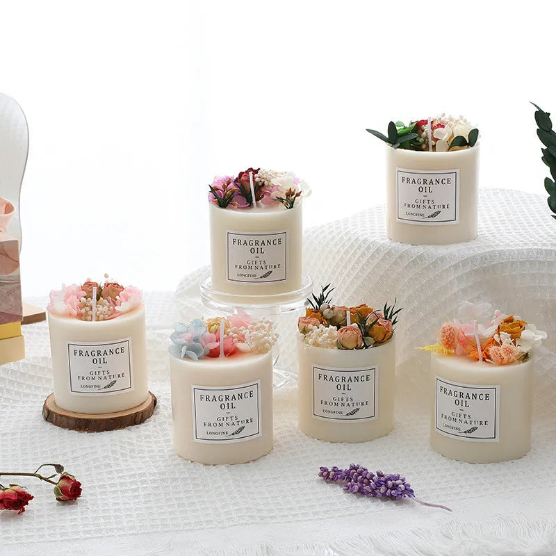 Decorative scented candle with dried flowers inside, shown with wood chip base and gift box.