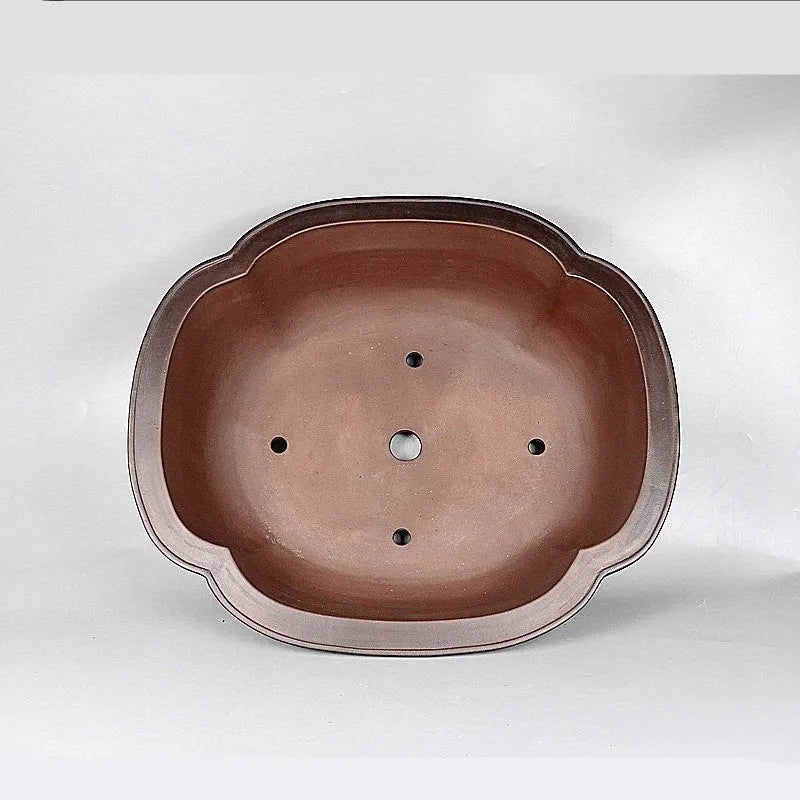 Handmade antique crabapple shaped large purple clay flowerpot on a floor.
